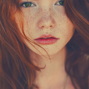 Young girl with red hair and freckles who is in need of sunscreen on her nose to protect her skin.